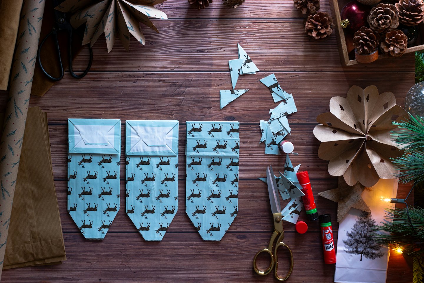 Christmas gift wrapping supplies arranged on a wooden table.